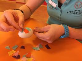 Bunte Papierschnipsel auf das Plastik-Ei anbringen