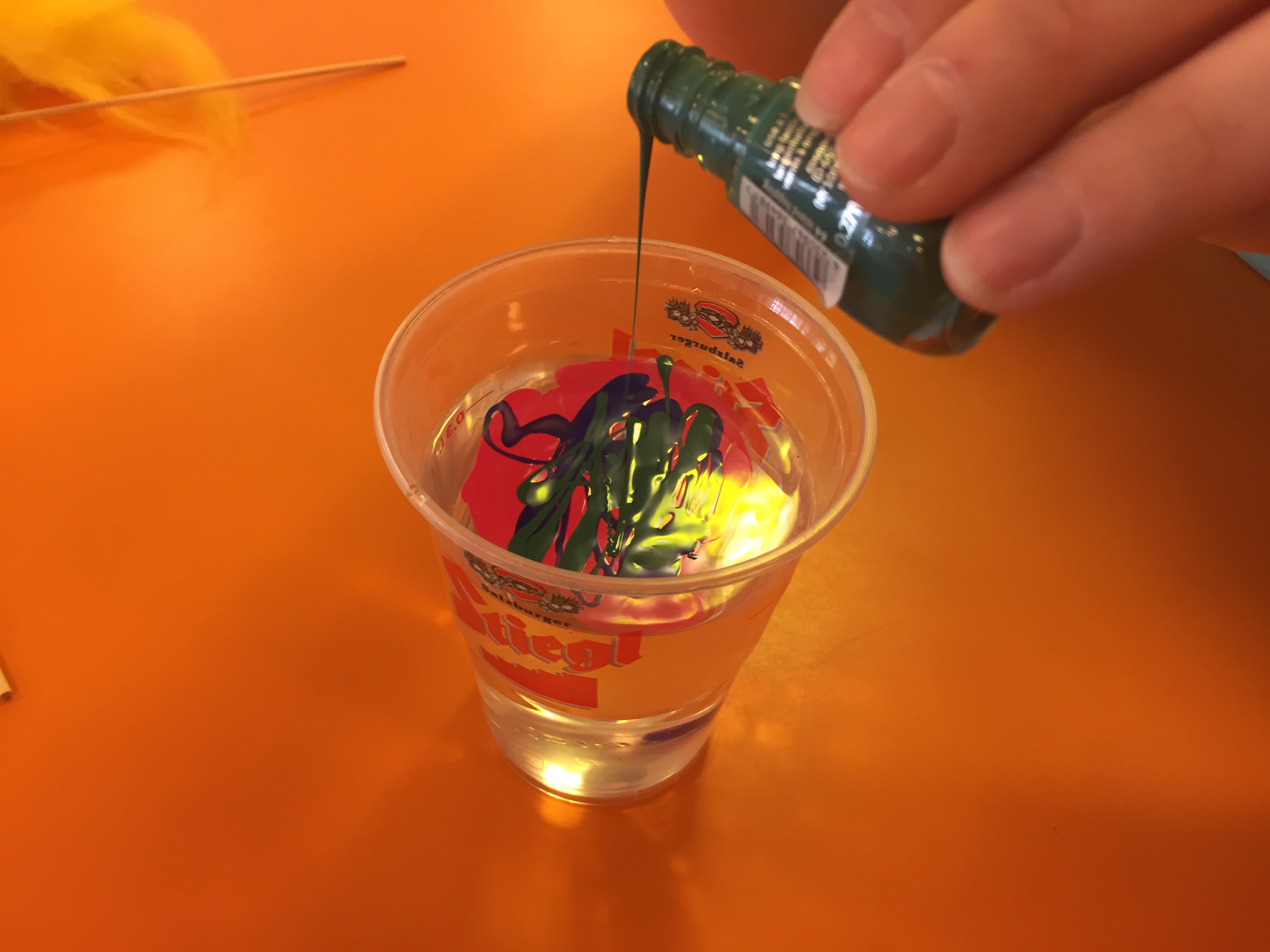 Nagellack in einem Becher mit Wasser tröpfeln